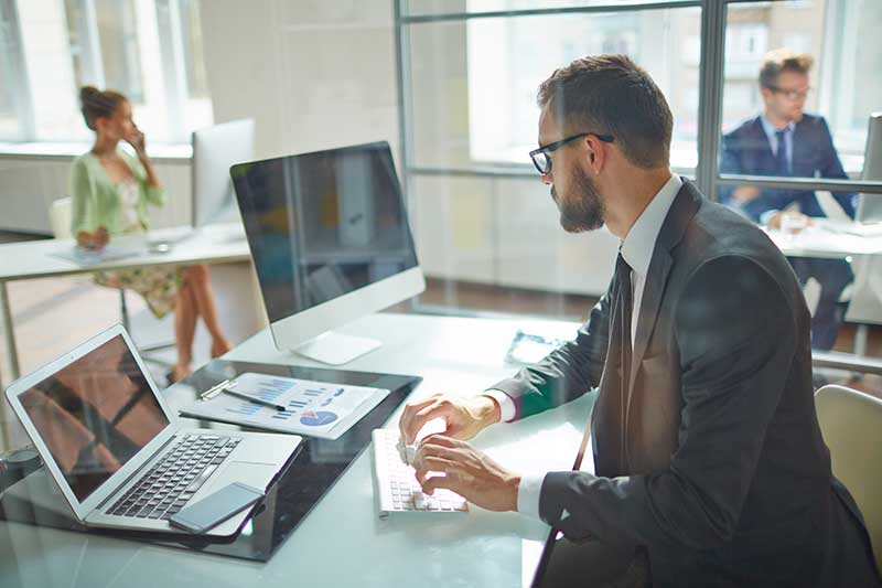 Mann schaut auf sein Business-Laptop im Büro