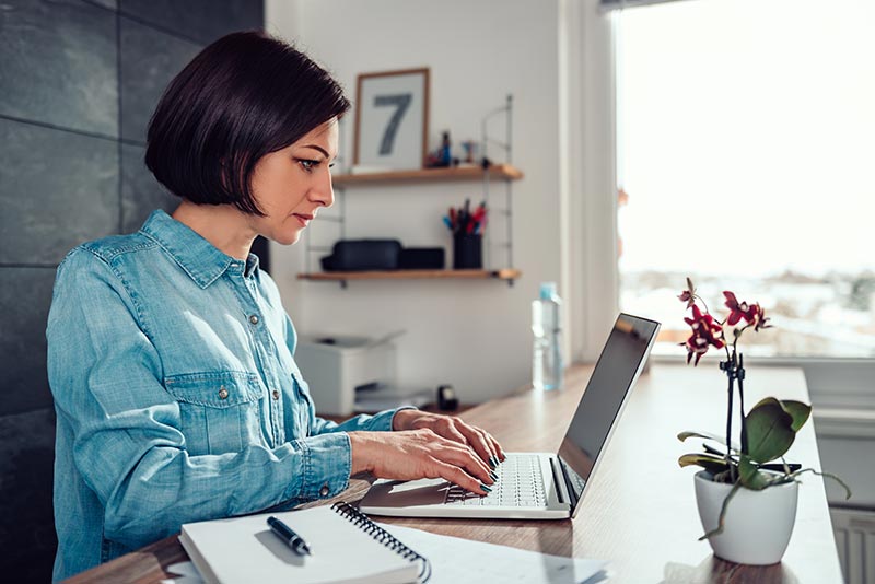 Sitz-Steh-Schreibtisch mit Frau am Arbeiten